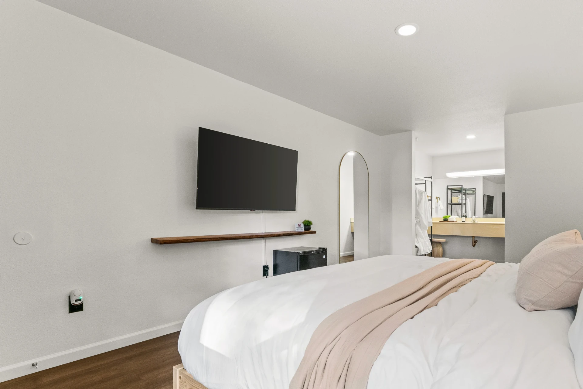 King bed with a wall-mounted TV and view toward the bathroom vanity