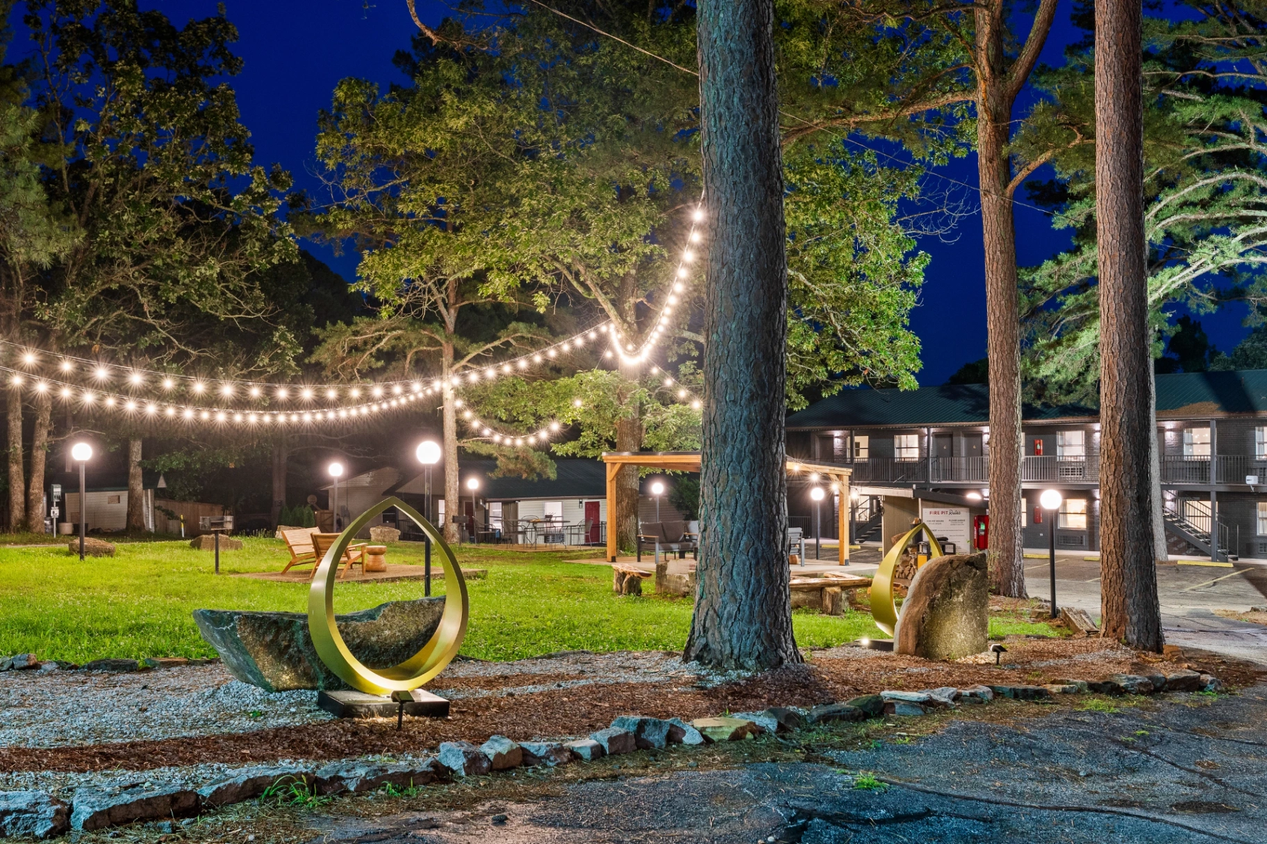 Forest Springs fire pit courtyard at night with string lights and Ozark pines