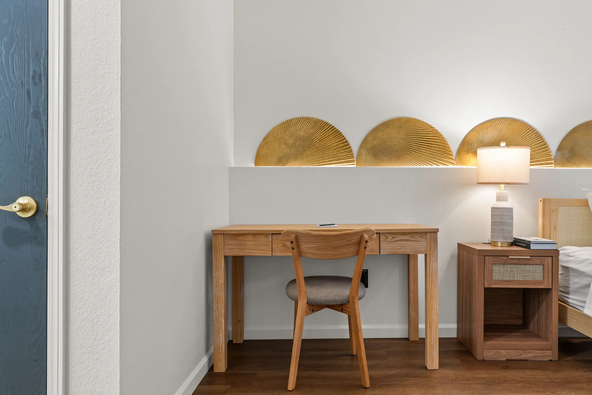 Wooden desk and chair beneath a lit brass fan wall detail
