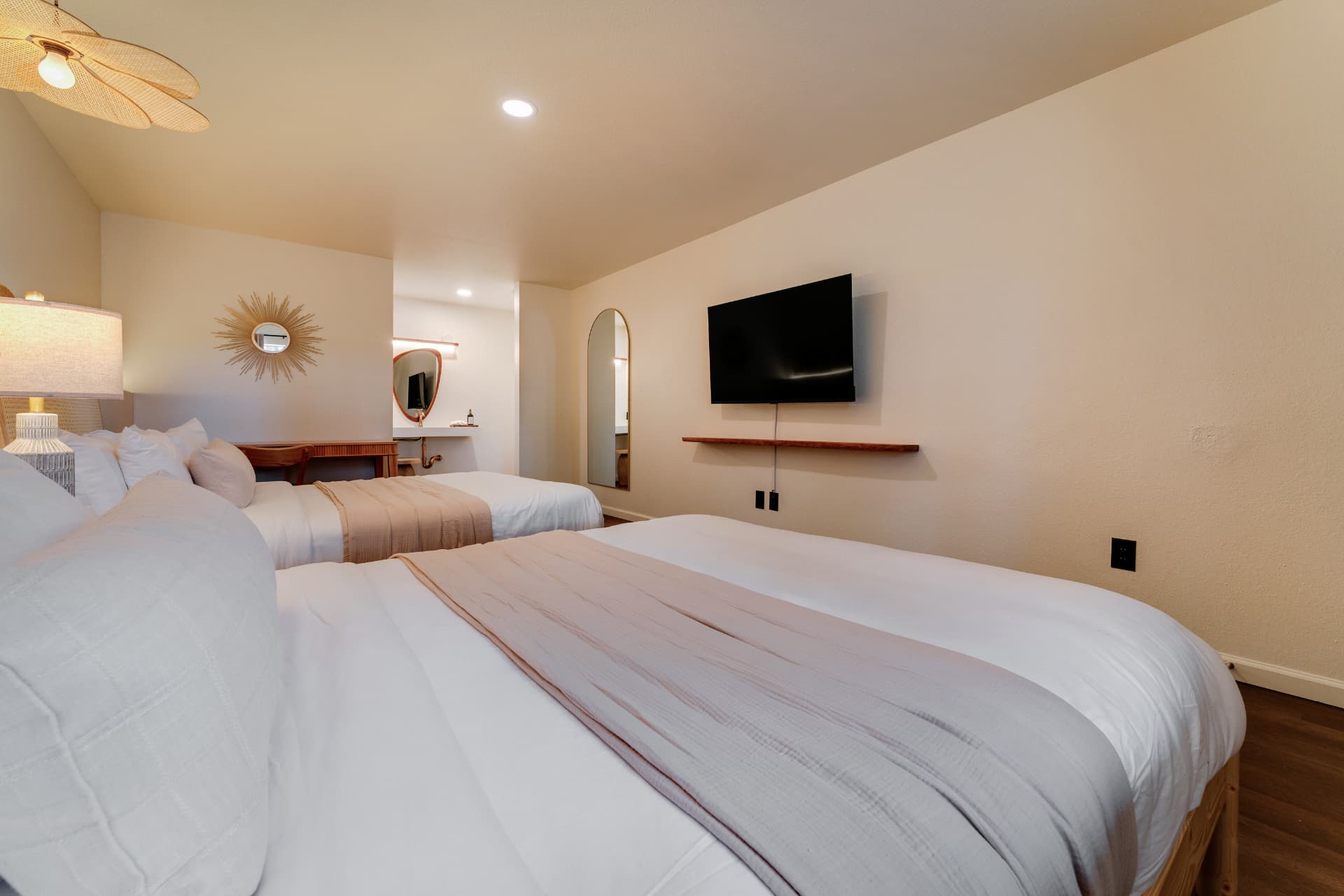 Two queen beds with wall-mounted TV and vanity nook