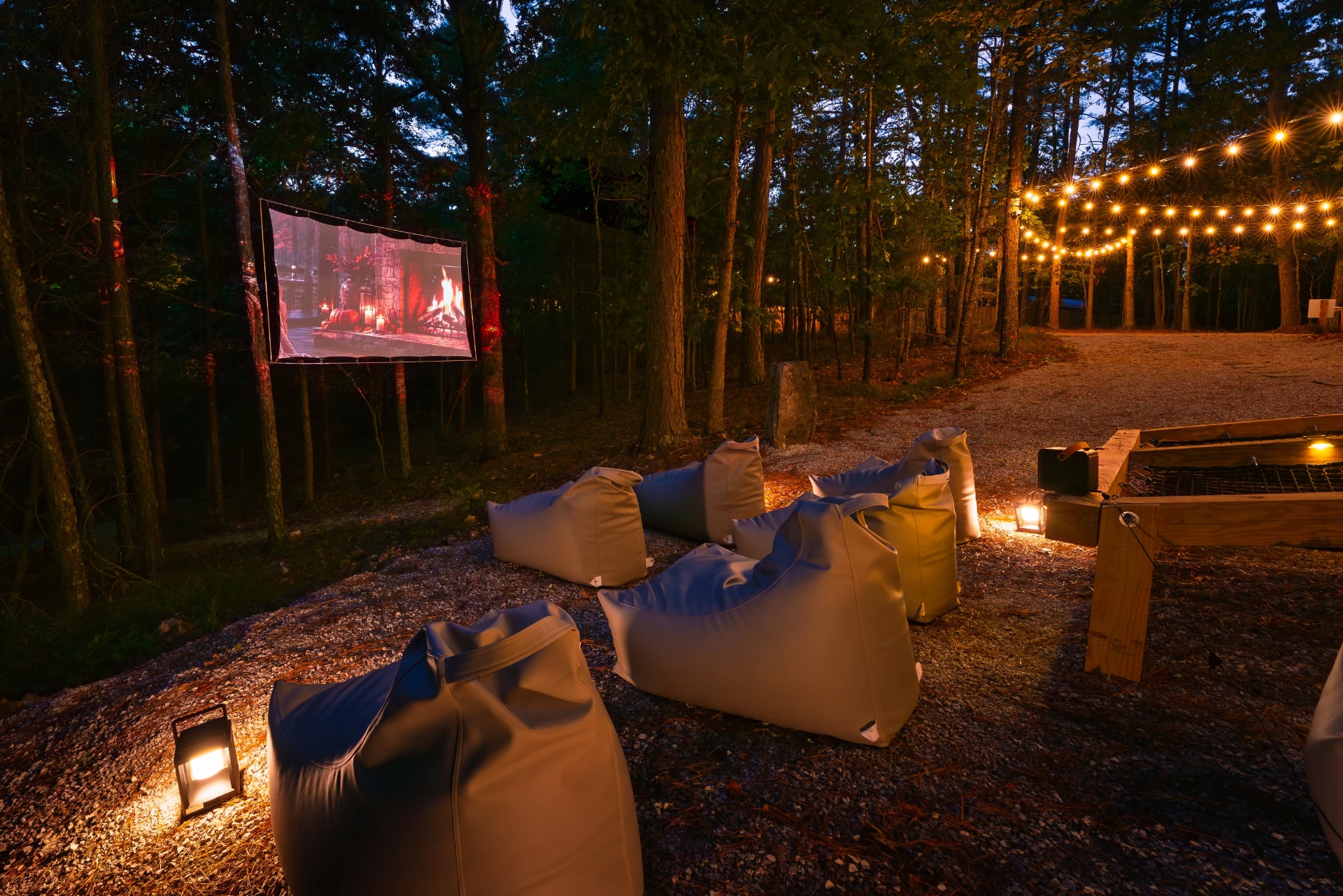 Outdoor movie screen among the trees with lanterns and string lights