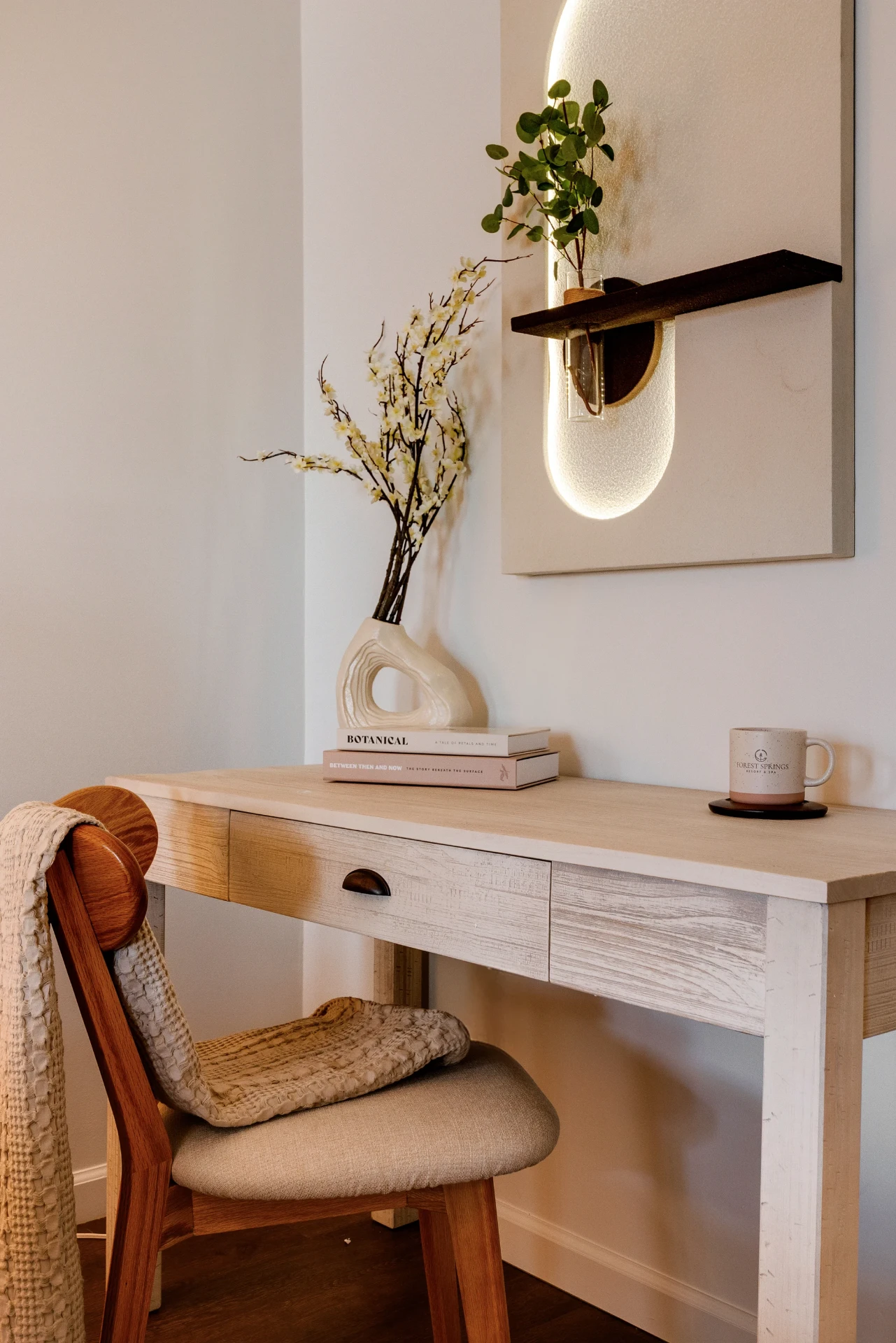 Desk nook with fresh branches and a Forest Springs mug