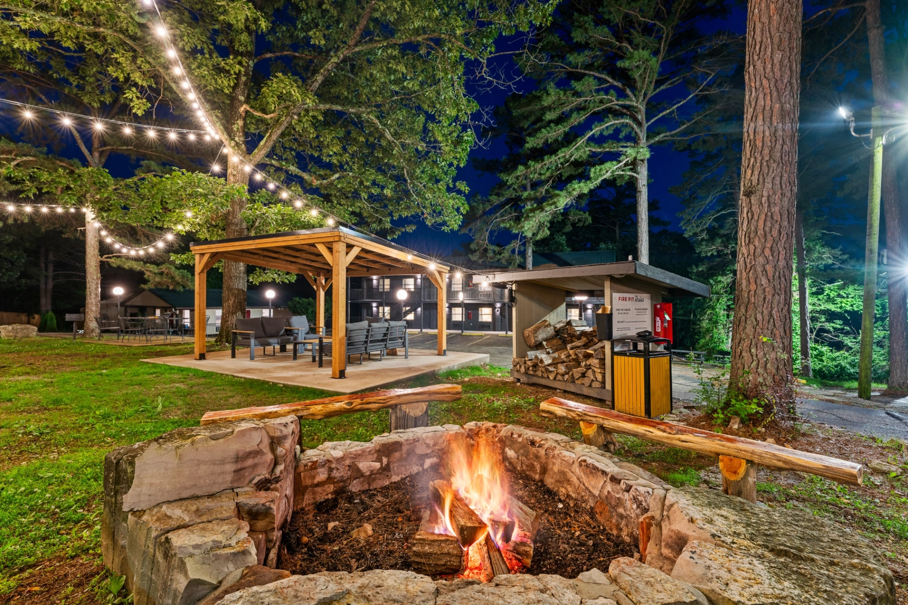Fire pit and string-lit pergola at night at Forest Springs