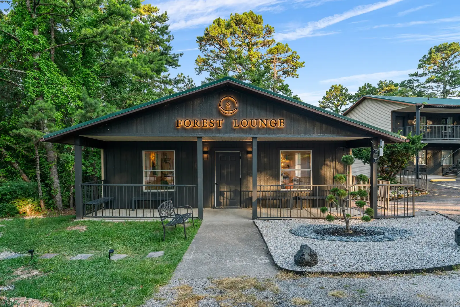 Exterior of the Forest Lounge building at Forest Springs Resort in Eureka Springs, with a covered porch and gravel garden