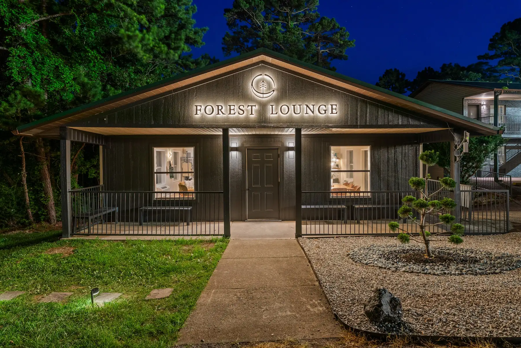 Forest Lounge at Forest Springs Resort at dusk with its sign, porch and windows lit against a deep blue sky