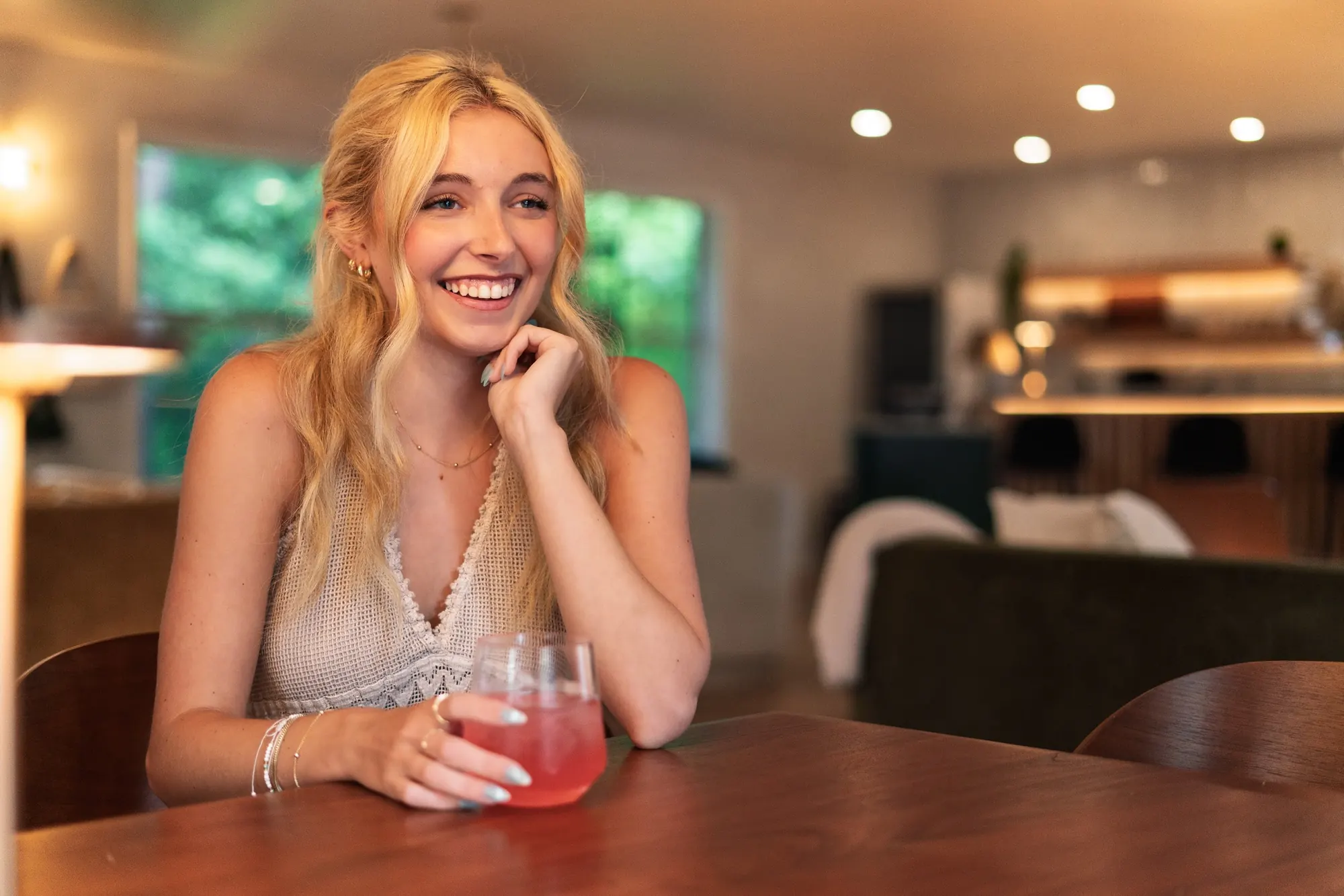 Smiling guest with a drink at a table in the Forest Lounge at Forest Springs Resort, Eureka Springs