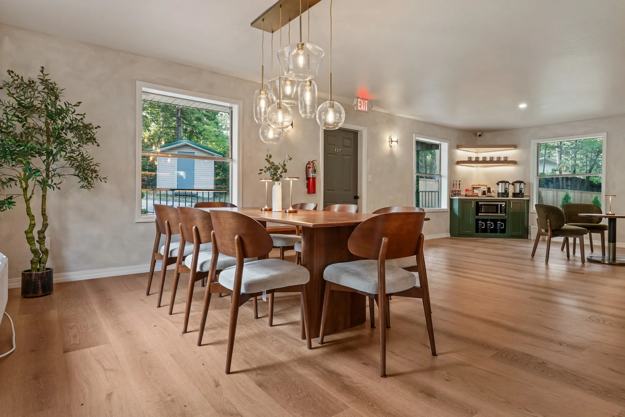 Long wooden dining table and chairs under glass pendant lights in the Forest Lounge at Forest Springs Resort