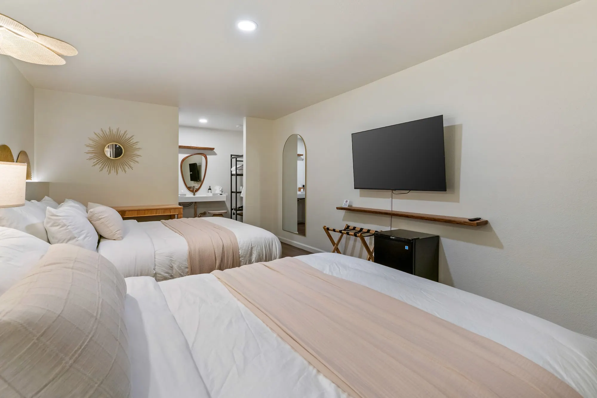 Guest room at Forest Springs Resort with two queen beds, wall-mounted TV, luggage rack and mini fridge