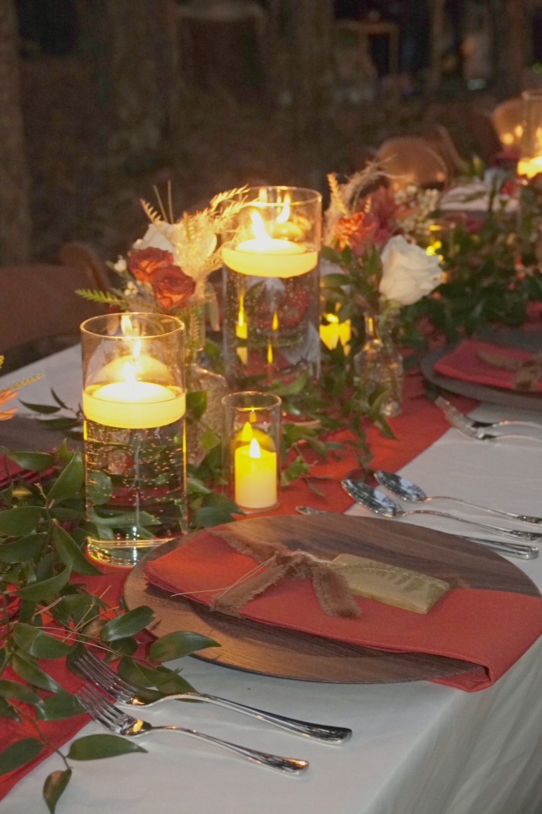 Candlelit dinner table with rust napkins and a greenery runner at Forest Springs Resort