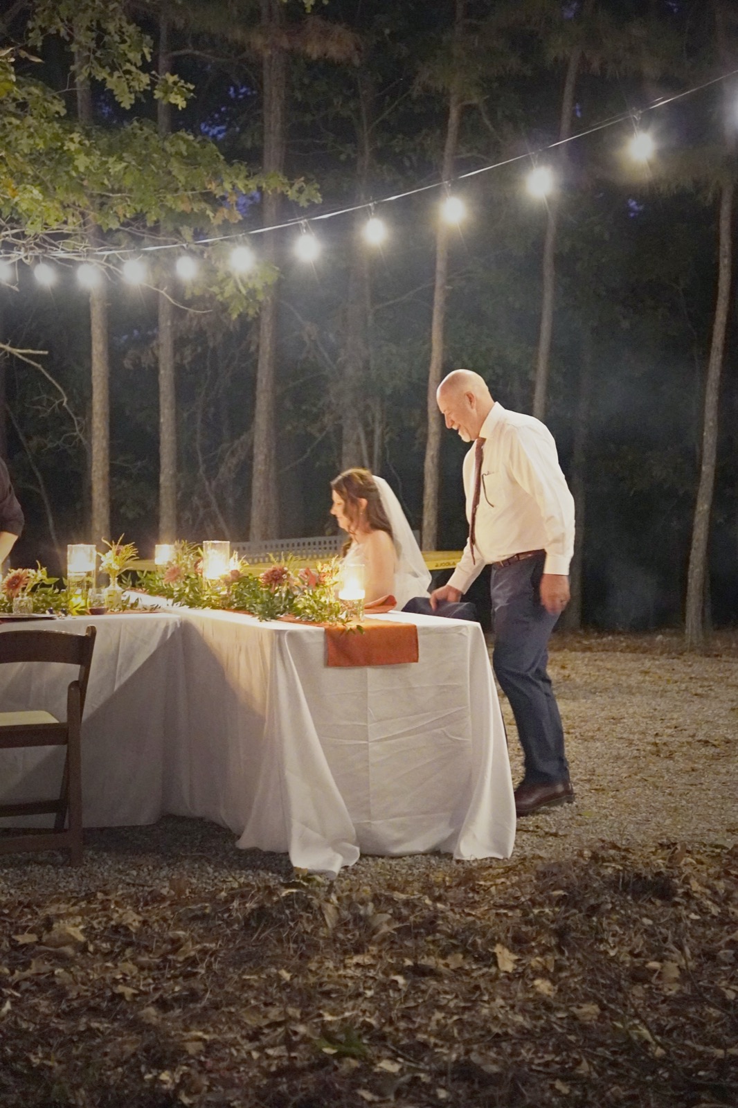 Couple at the head table under the pines at night