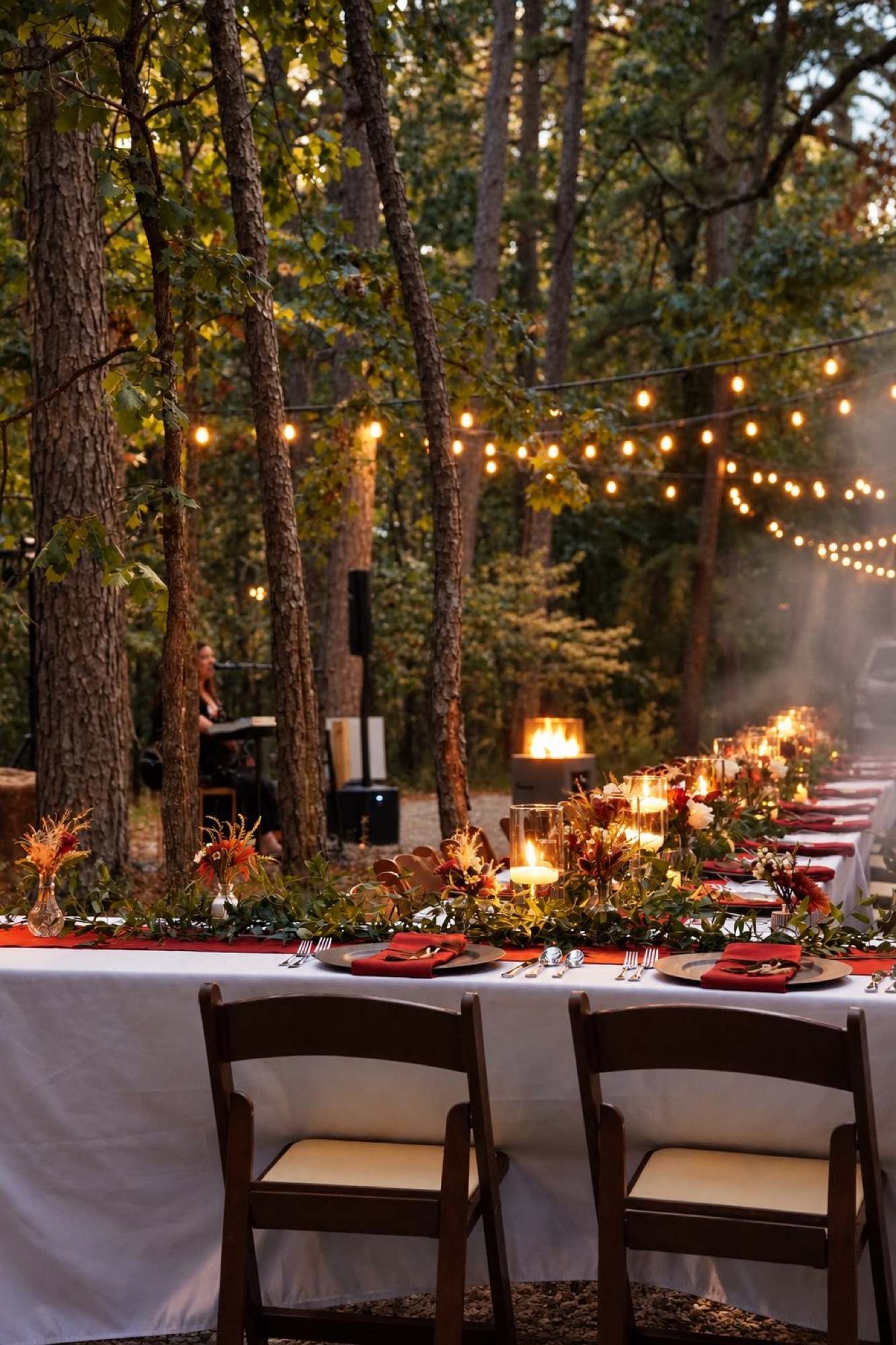 Long candlelit dinner table under string lights in the forest at Forest Springs Resort