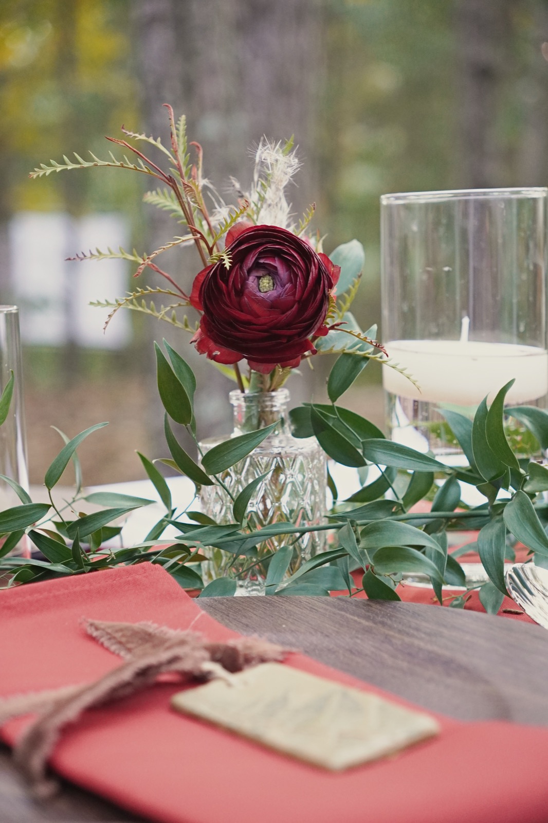 Burgundy ranunculus centerpiece with candles on a dinner table at Forest Springs Resort