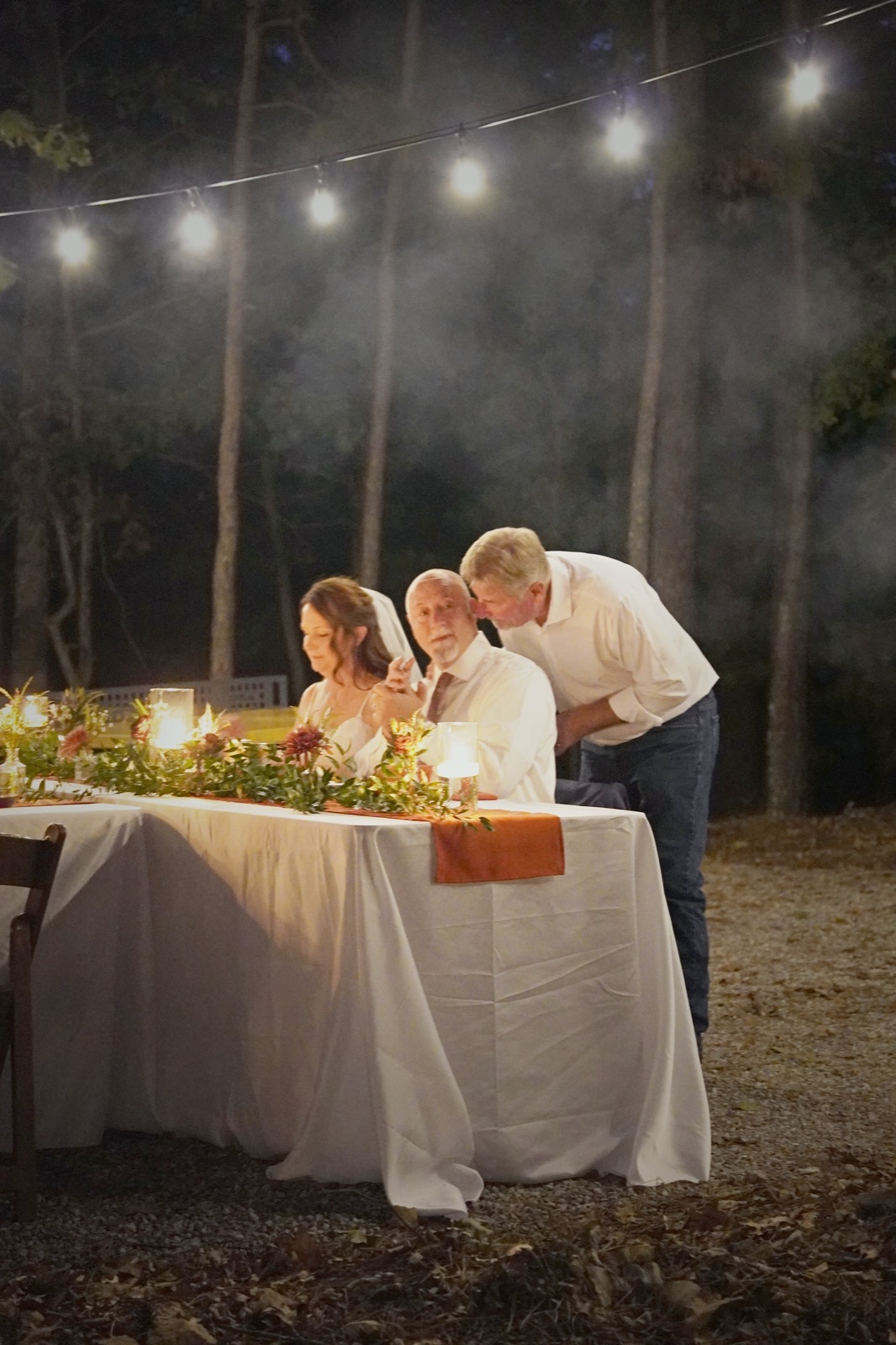 A guest leaning in to talk with the couple at the head table